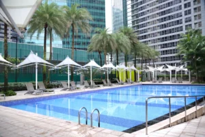 Resort swimming pool with palm trees and shade.