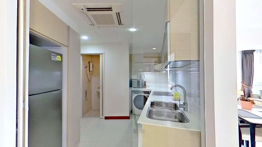 Modern apartment kitchen with refrigerator, sink, and door.