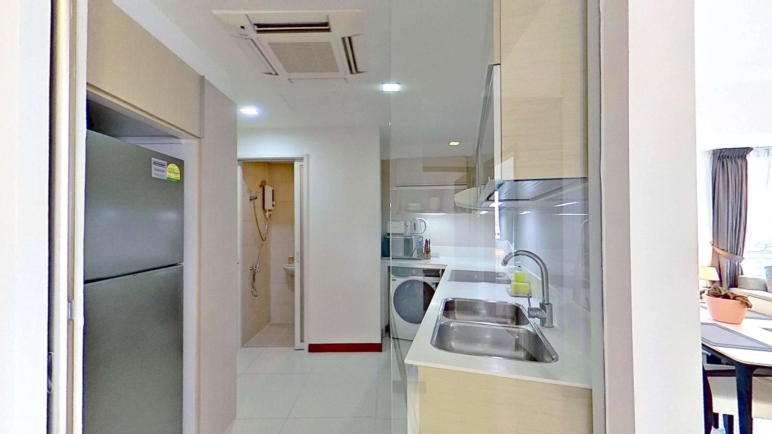 Modern apartment kitchen with refrigerator, sink, and door.