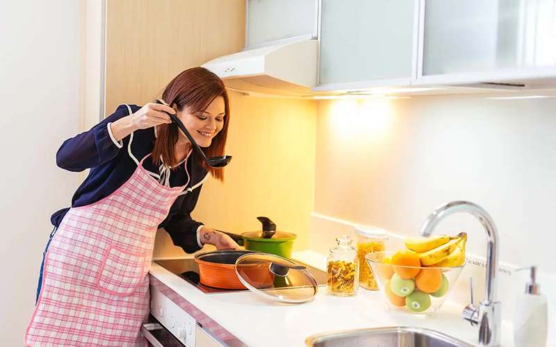 Woman cooking a meal in a serviced apartment kitchen.